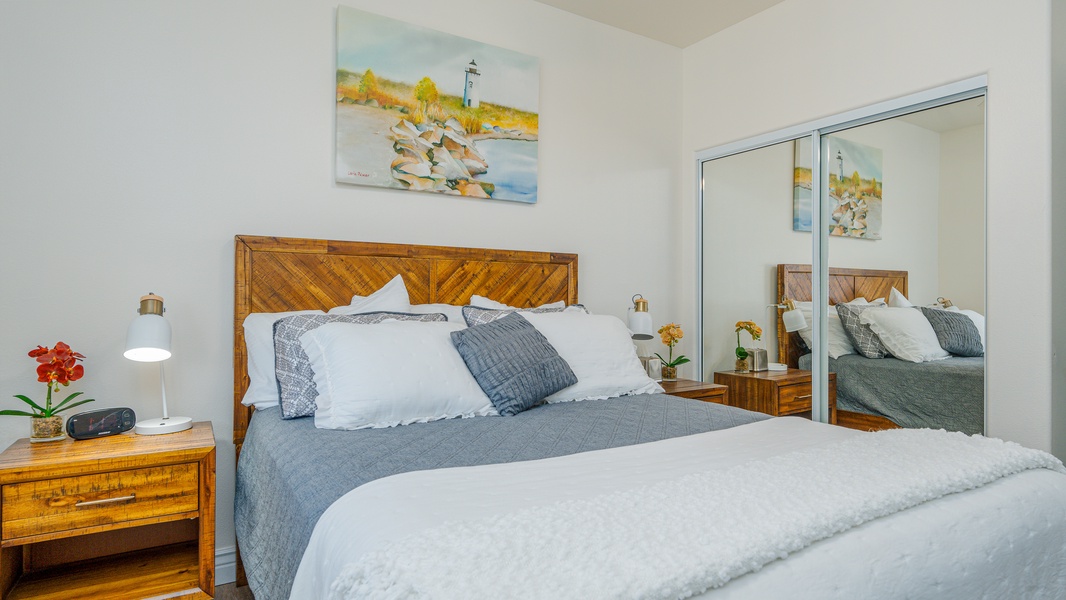 The second guest bedroom with soft bedding on a queen bed and natural lighting.