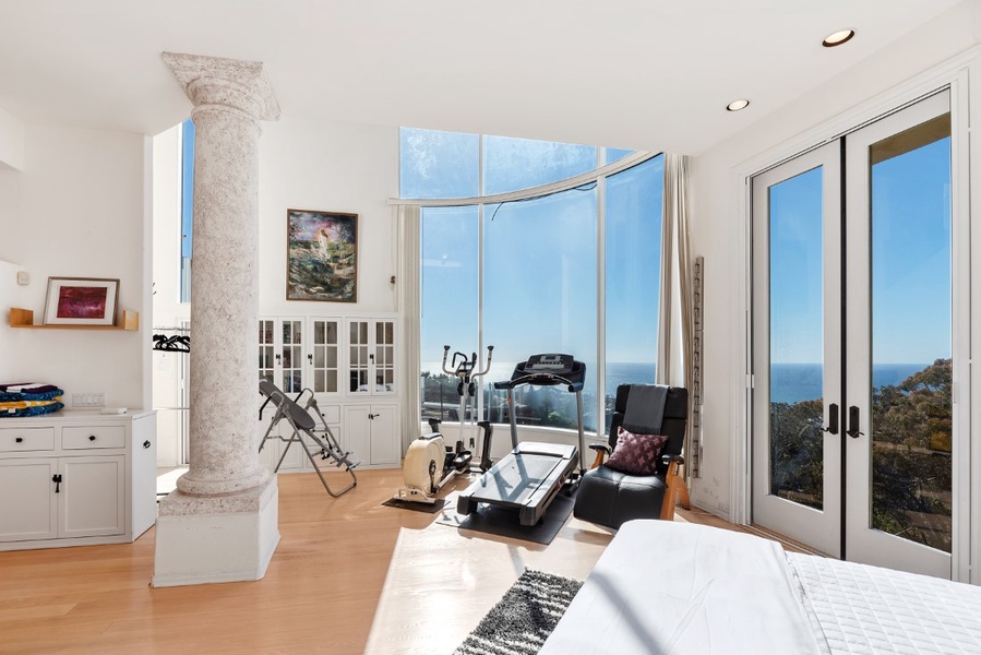 Lowest-level Poolside gym/bedroom with floor to ceiling curved glass has fitness equipment with spectacular panoramic views