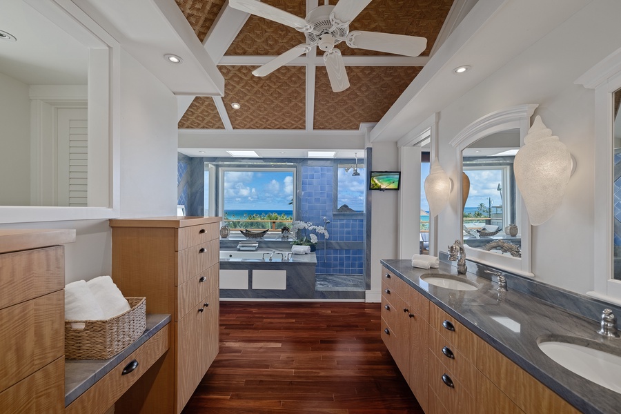 Spacious primary bathroom with dual vanities, a soaking tub, and a view to enjoy while you unwind.