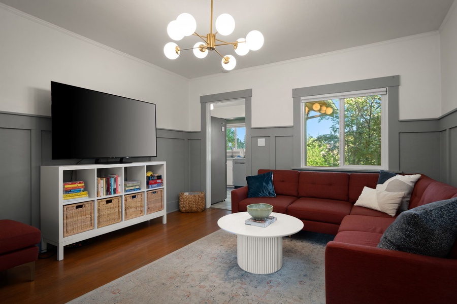 Relax in your bright living room with stylish furnishings, ample storage, and natural light streaming through large windows overlooking lush greenery.