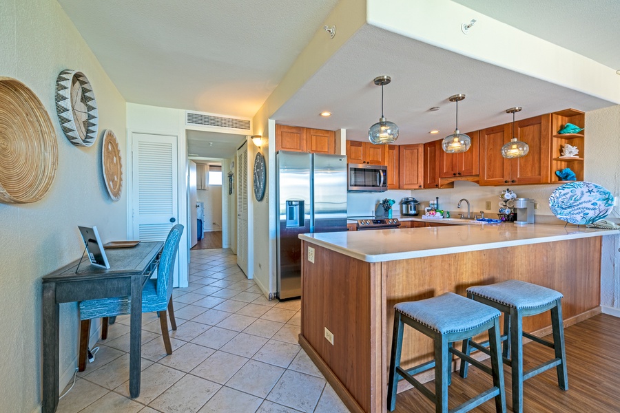 The kitchen features modern appliances, a large fridge, and a spacious island with seating for casual dining or meal prep.