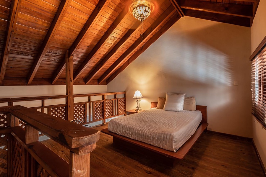 Charming loft bedroom with wooden beams and a cozy ambiance.