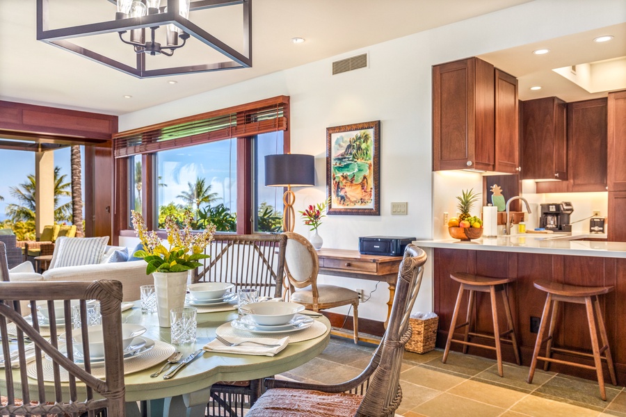 Close up of dining table with desk and kitchen bar seating in background.