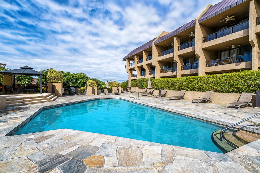 Large sparkling pool surrounded by palm trees and sun loungers.