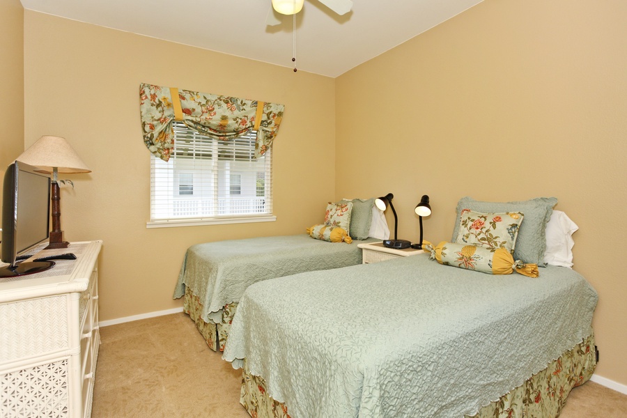 The third guest bedroom with two beds and a dresser.