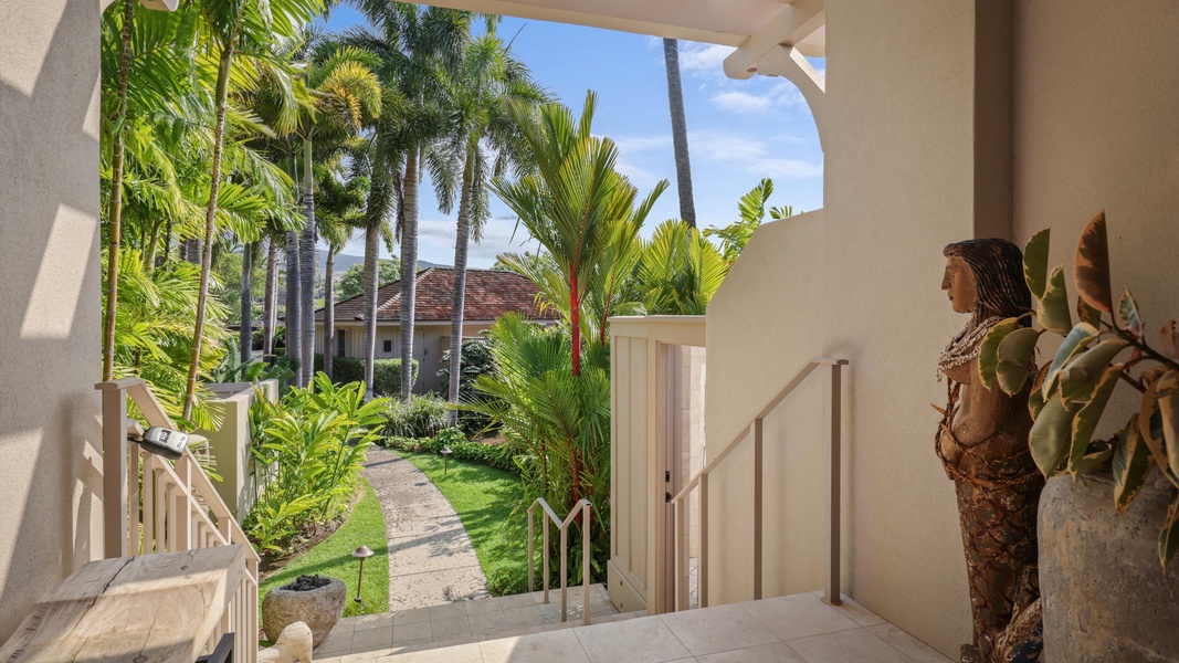 Tropical entryway lined with palms and lush greenery.