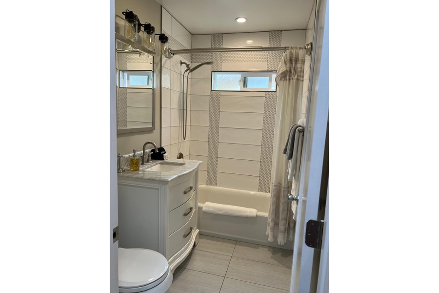 The full bathroom has a single vanity and tub with a shower.