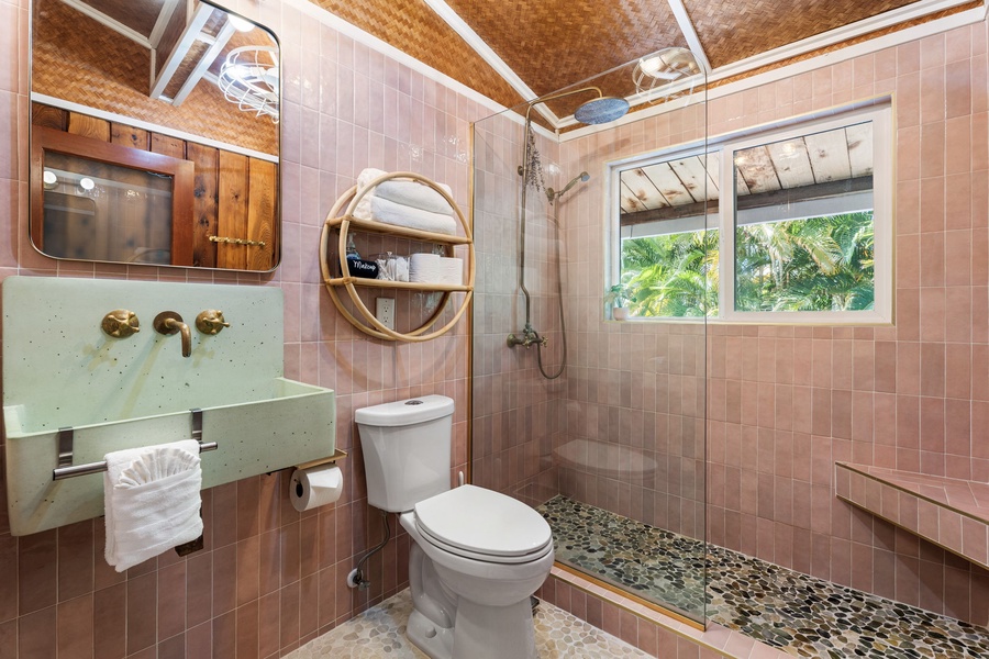Refresh in your private bathroom with stylish subway tiles, a rainfall shower, and tropical garden views through the window.
