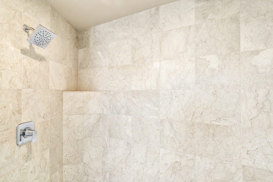 Walk-in shower with natural stone tile in the guest bathroom—spacious and sleek.