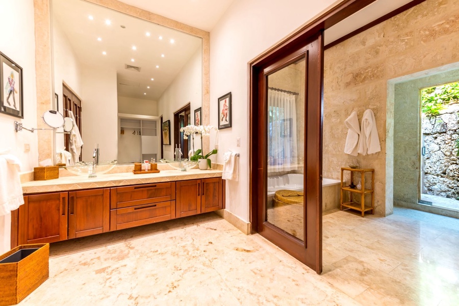 Elegant ensuite bathroom with large vanity, double sink, and an access to an outdoor shower area.