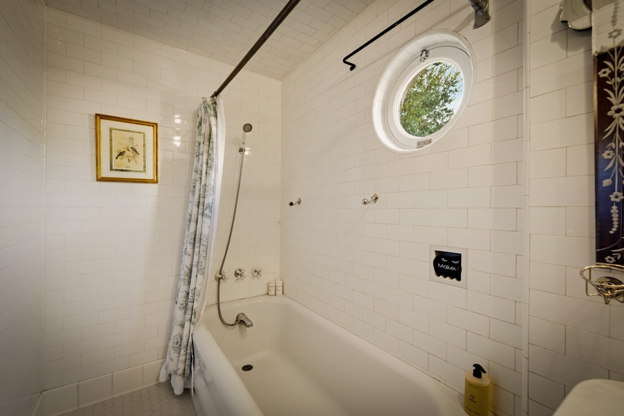 Unwind in your charming subway-tiled bathroom, where natural light streams through the porthole window as you soak in the deep tub.