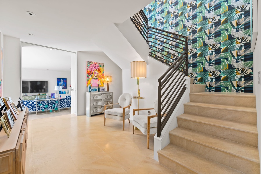 Bright stairway accented with tropical wallpaper, modern railing, and warm tones.