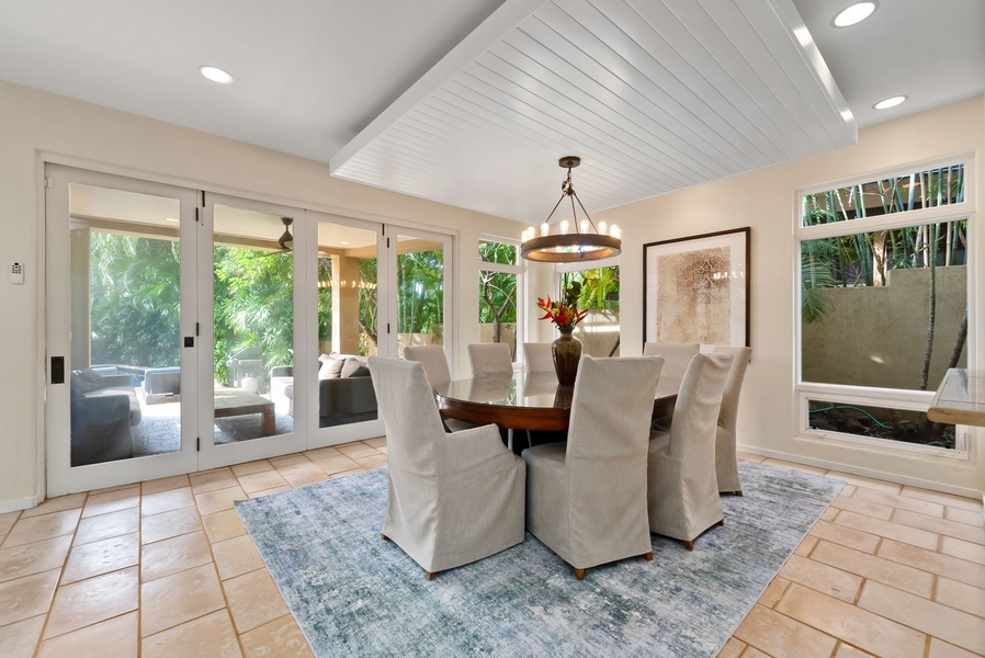 Gather around this elegant dining table where natural light streams through windows overlooking lush tropical gardens, creating the perfect setting for memorable meals.