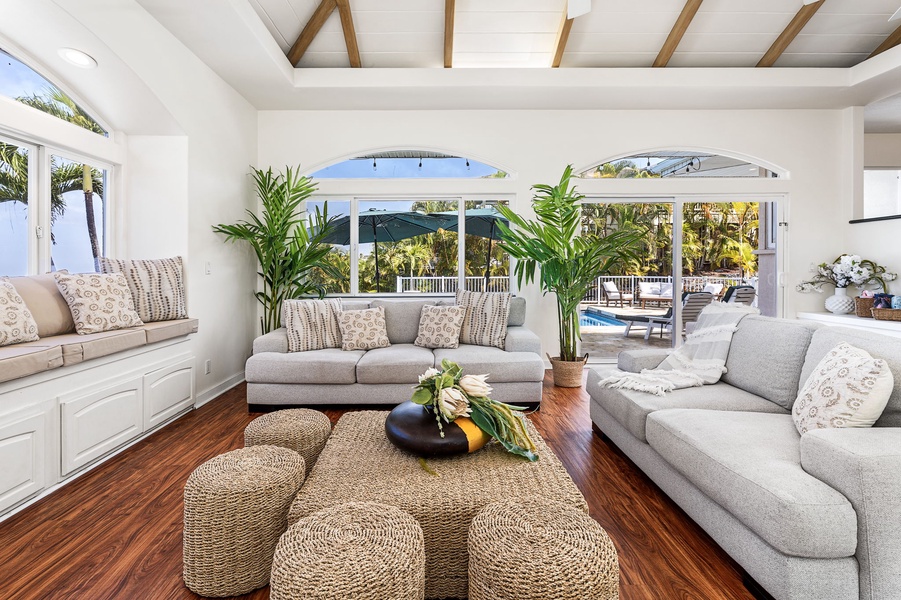 Plush seating while tropical palms frame your pool views through elegant arched windows.