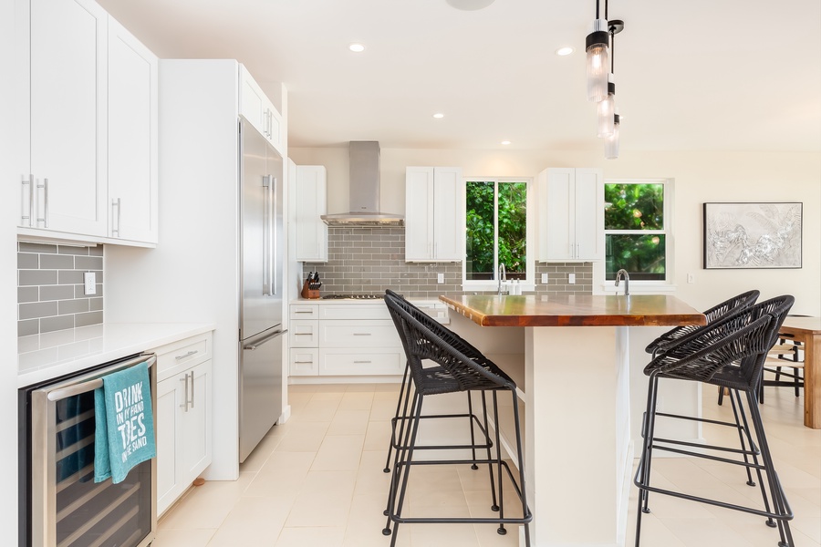 Kitchen island with bar seating and a backdrop of modern cabinetry and stainless appliances.