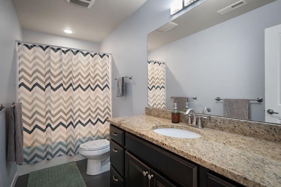 The full guest bathroom includes a granite vanity, shower-tub combination, and bright finishes for everyday convenience.