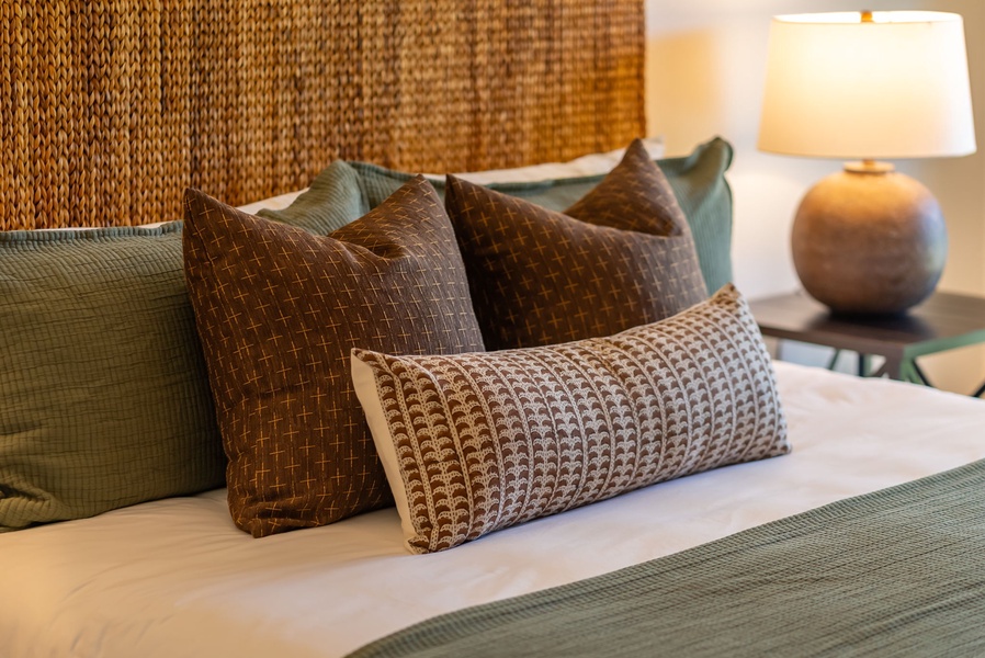 Sink into the plush comfort of your perfectly made bed, adorned with layered textured pillows and a warm bedside lamp creating a cozy, inviting retreat.