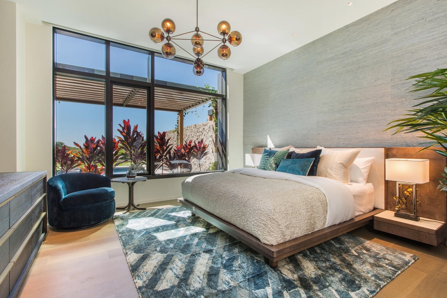Sink into your luxurious platform bed beneath the stunning chandelier, where tropical garden views flood your serene retreat with natural light.