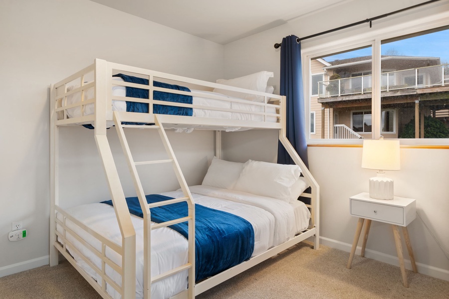 Drift off in your cozy bunk bed with crisp linens and ocean-blue accents, perfect for peaceful nights in this bright, airy room.