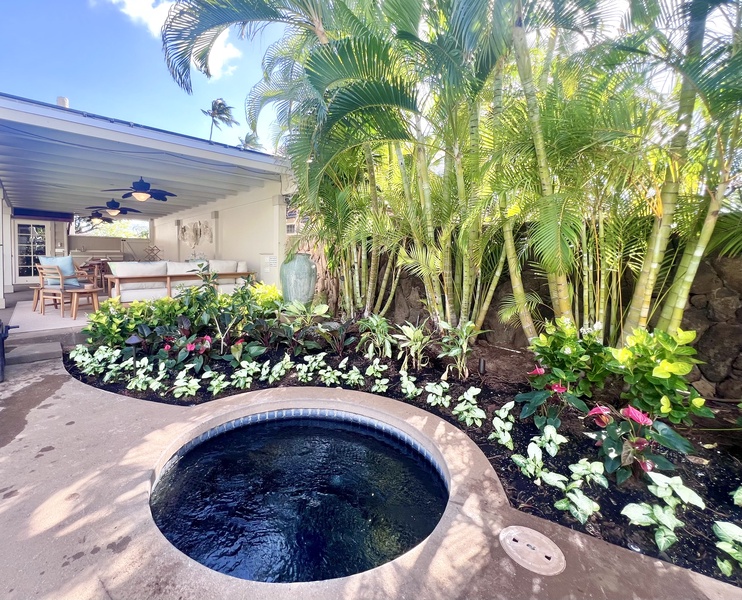 Relax and unwind in the private outdoor spa, surrounded by lush tropical plants and vibrant flowers for a serene retreat.