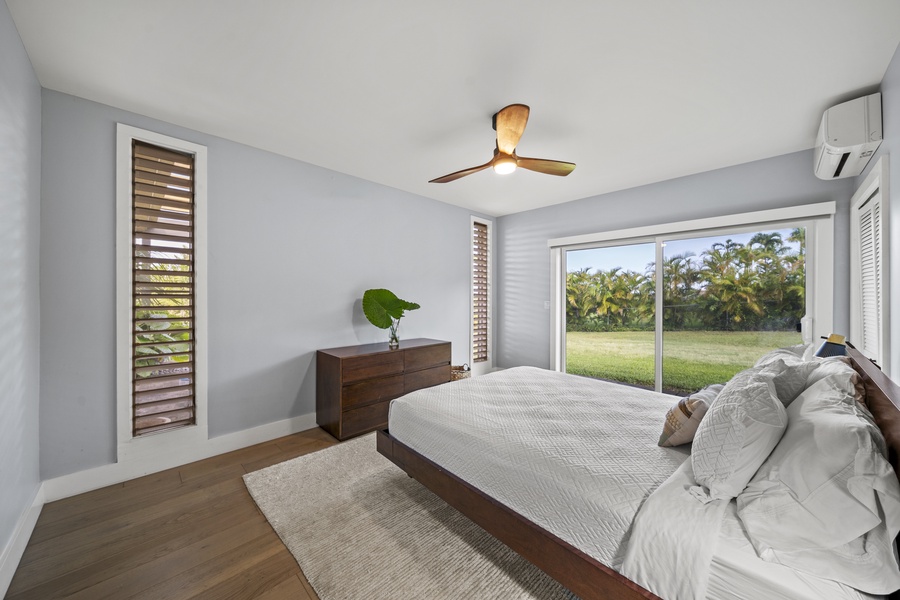 Bright bedroom with a queen-sized bed, dresser, and ceiling fan for added comfort.