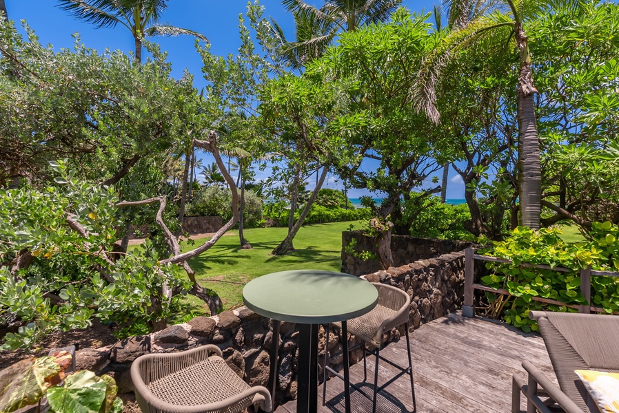 Private beachfront lanai framed by lush tropical gardens offers breathtaking sea views and peaceful outdoor dining beneath swaying palms.