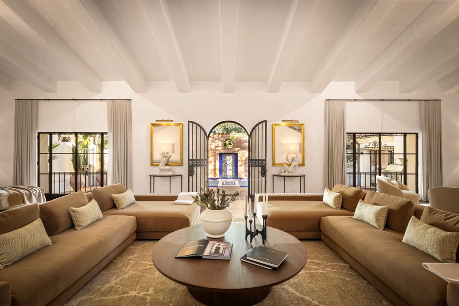 Symmetry and serenity define this refined living room, where arched French doors and a beamed ceiling create a sense of calm grandeur.