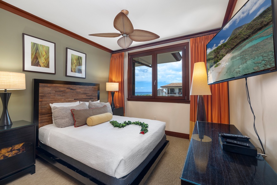 Unwind in your elegantly appointed bedroom featuring a plush king bed, tropical ceiling fan, and stunning ocean views through your private window.
