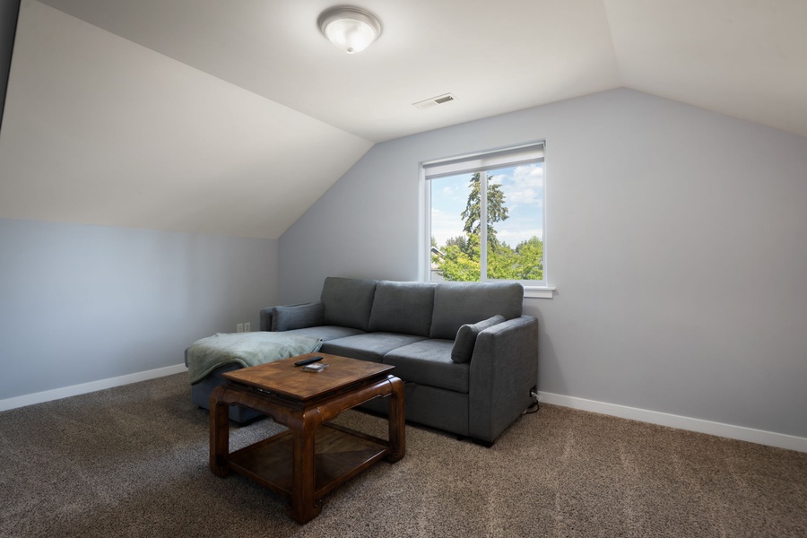 This comfortable upstairs retreat features soft seating, a mounted TV, and flexible space for relaxing during extended stays.