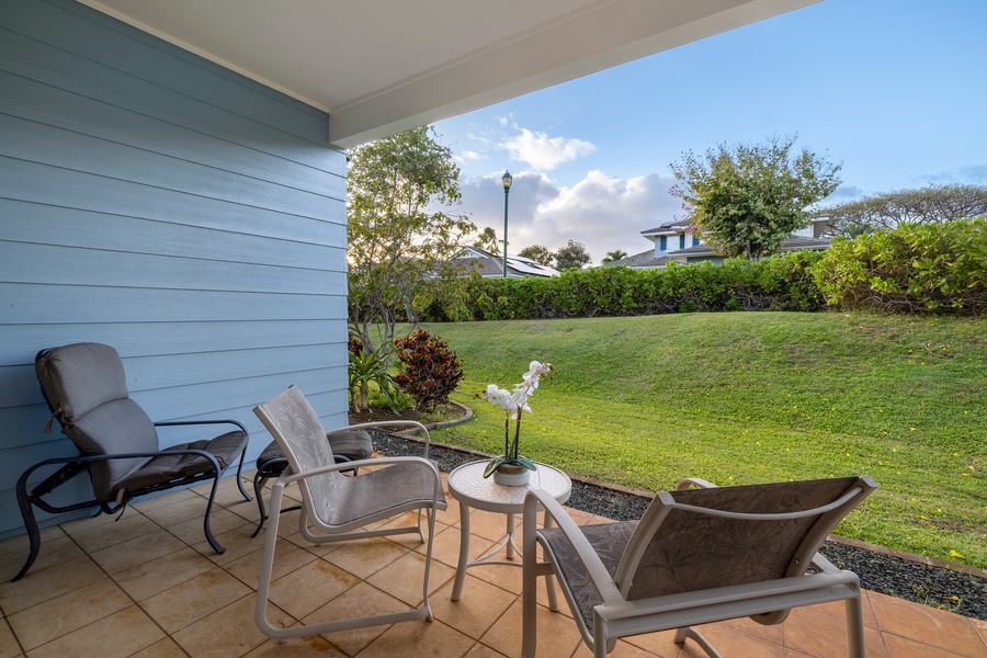 Relax in your private outdoor seating area overlooking manicured gardens, where comfortable chairs invite peaceful moments under the covered lanai.