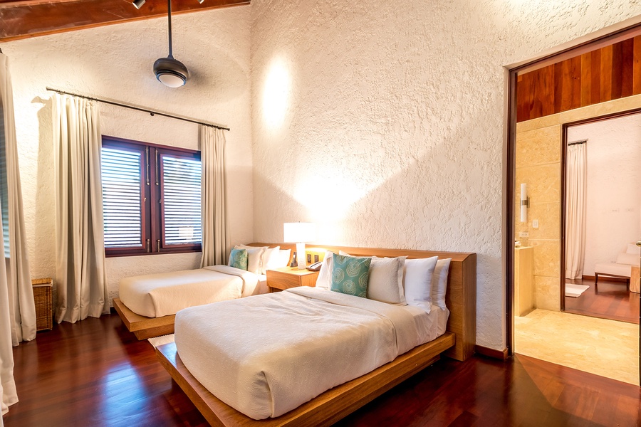 This guest bedroom has two queen beds and warm lighting.