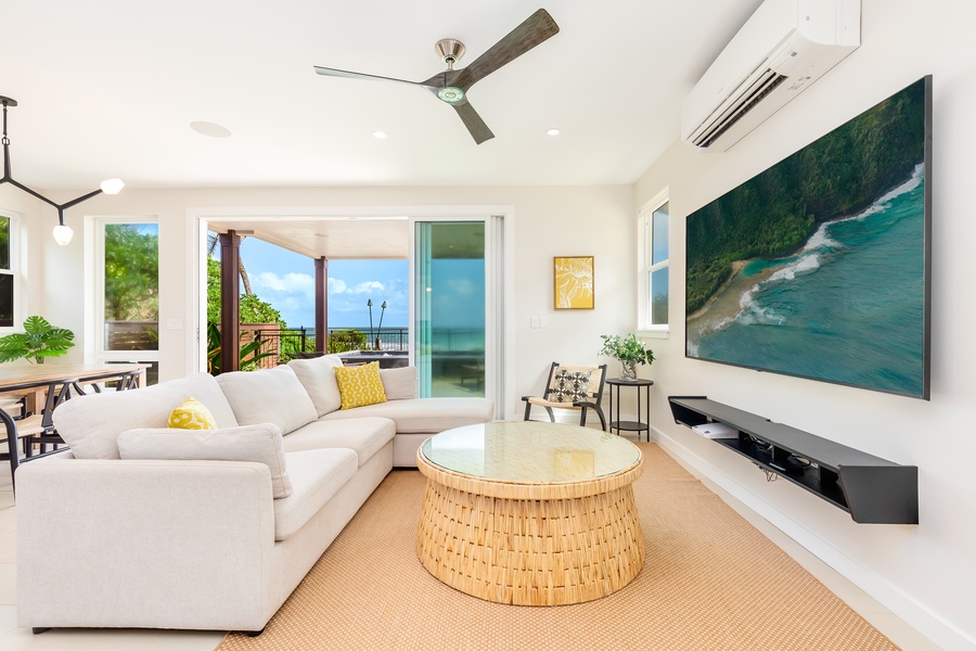 Living room accented with natural tones, wall-mounted TV, and expansive ocean views.