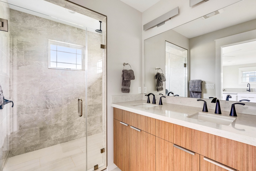 Ohana bathroom with dual vanities and walk-in shower with a glass enclosure.