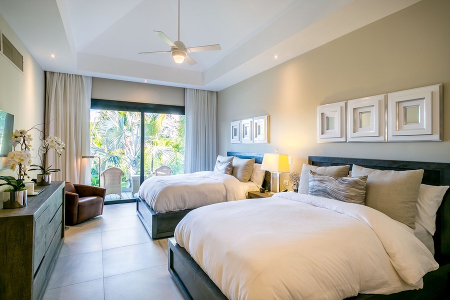 Enjoy this cozy guest bedroom with two comfortable beds and a private balcony overlooking the lush garden.
