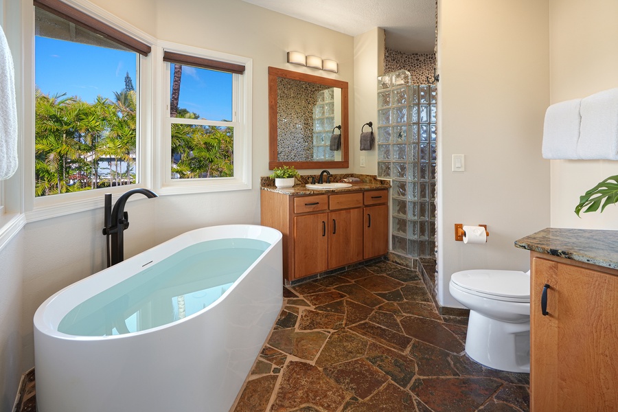 Soak in your luxurious freestanding tub while gazing at tropical palms through picture windows in this spa-inspired bathroom retreat.
