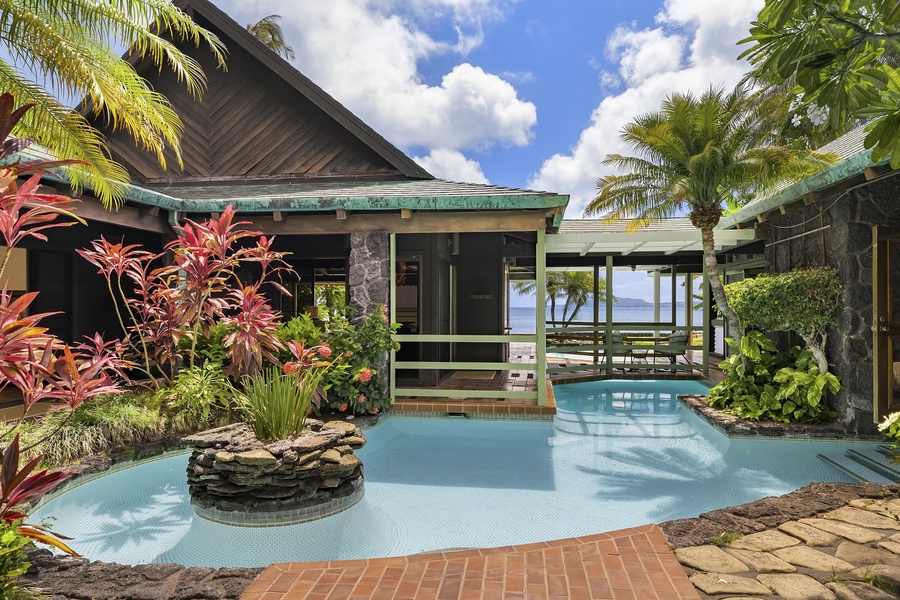 Large resort-style pool meanders through courtyard towards oceanfront lawn.