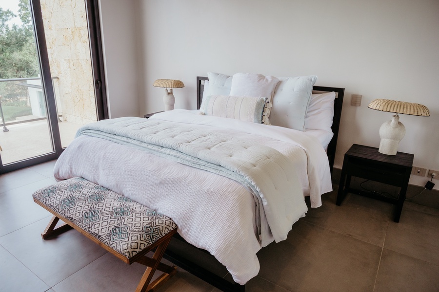 Comfortable bed and modern decor in the guest bedroom with private patio.