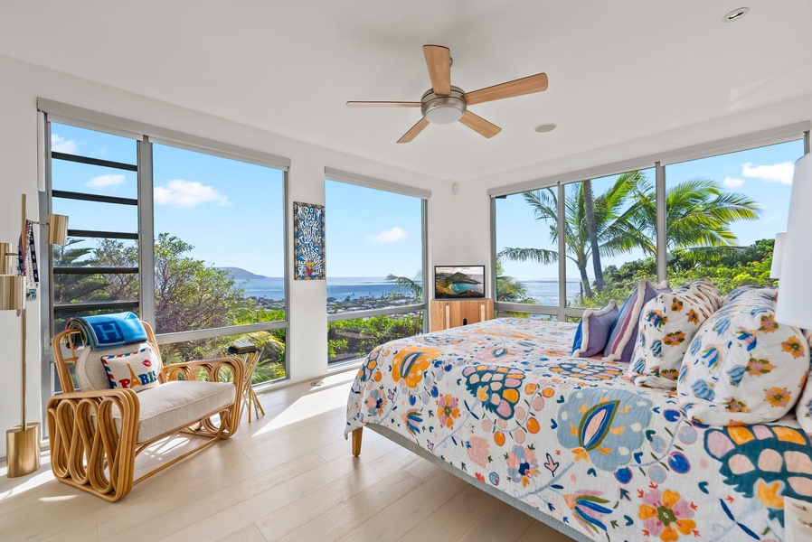 Vibrant second bedroom with panoramic windows, ocean views, and colorful bedding.