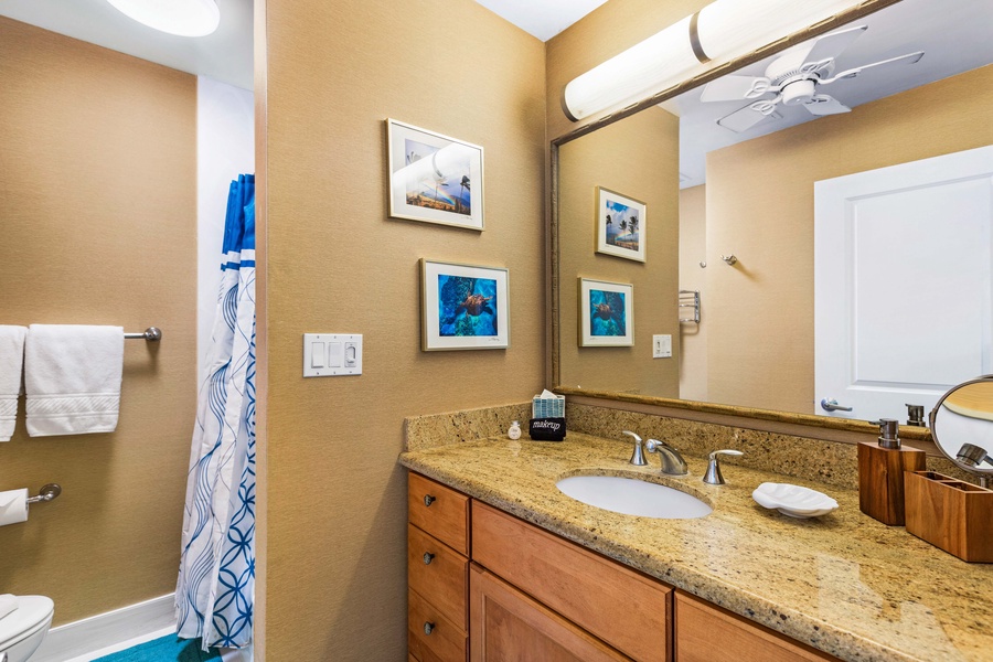 A well-lit bathroom with granite countertops and charming wall art, offering a clean and relaxing space.