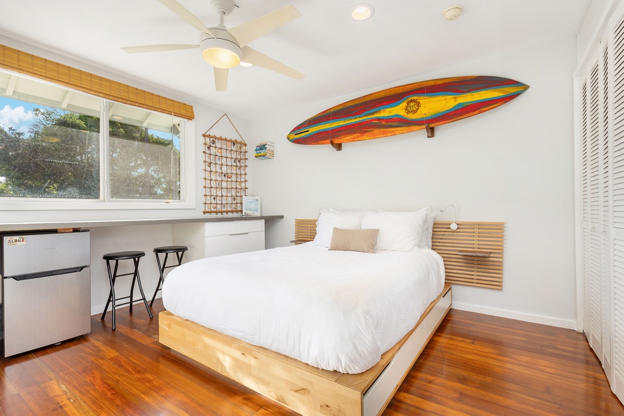 Studio bedroom with king bed, surf-inspired decor, smart TV, and a built-in desk for remote work or planning your next adventure.