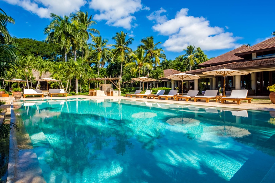 Luxurious pool with ample sun loungers and tropical garden.