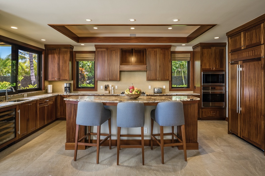 Alternate view of kitchen showcasing spacious layout, bar seating and chic recessed lighting.