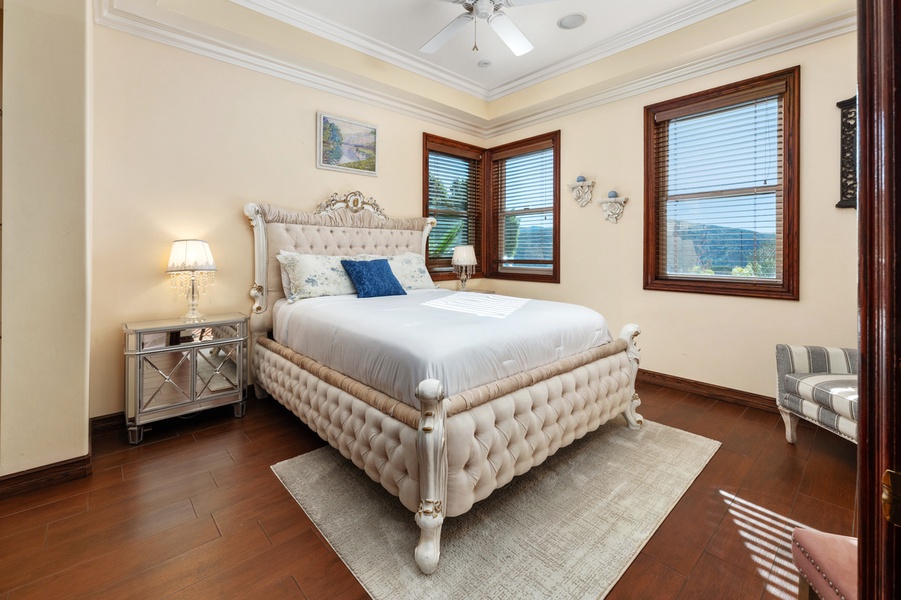 The tufted bed faces the window, daylight already filling the room.
