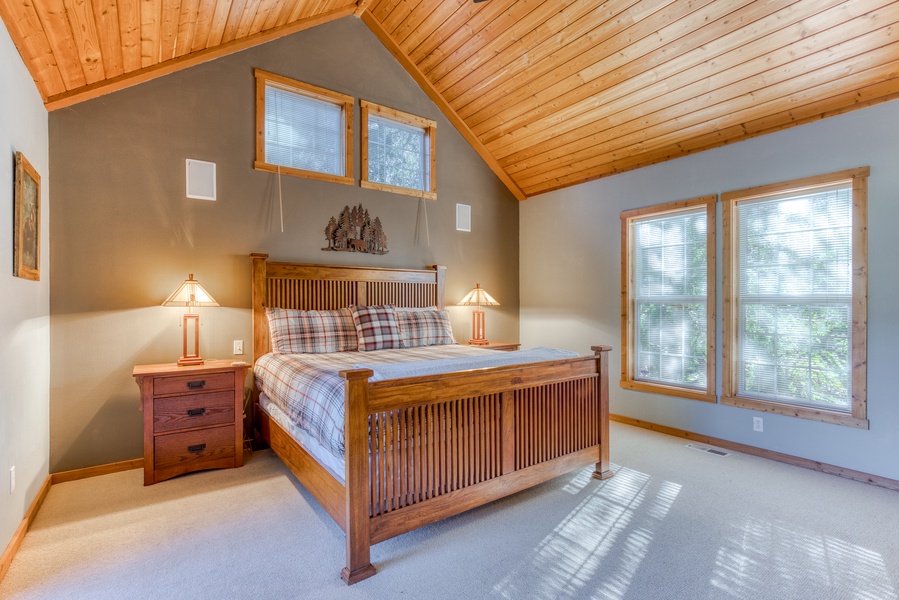 Guest room with king bed with  warm wood accents and natural light.