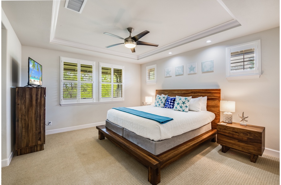 Primary bedroom, equipped with a king bed, ceiling fans, a television, and private balcony