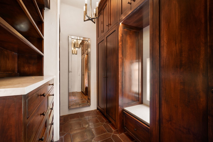 Your private walk-in closet features rich wood cabinetry with ample storage, a cozy seating nook, and warm lighting for your daily routines.