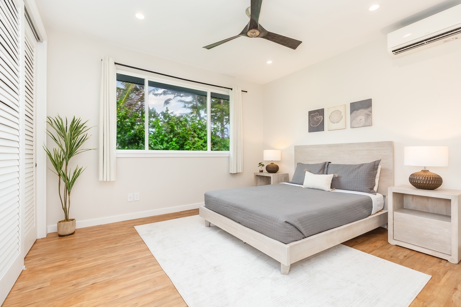 Stylish second guest bedroom offering soft neutral tones and large windows overlooking the gardens.