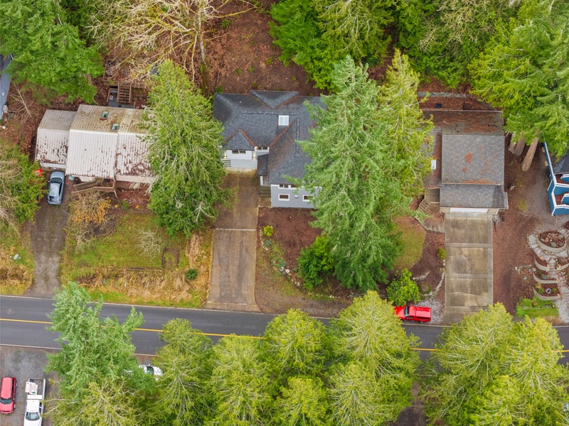 Aerial view of a charming residential property nestled among mature trees and landscaped grounds in a quiet neighborhood setting.