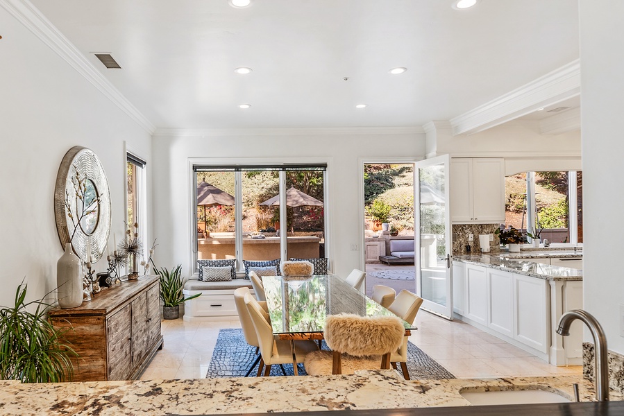 French doors to the outdoor kitchen and pool areas from the informal dining.