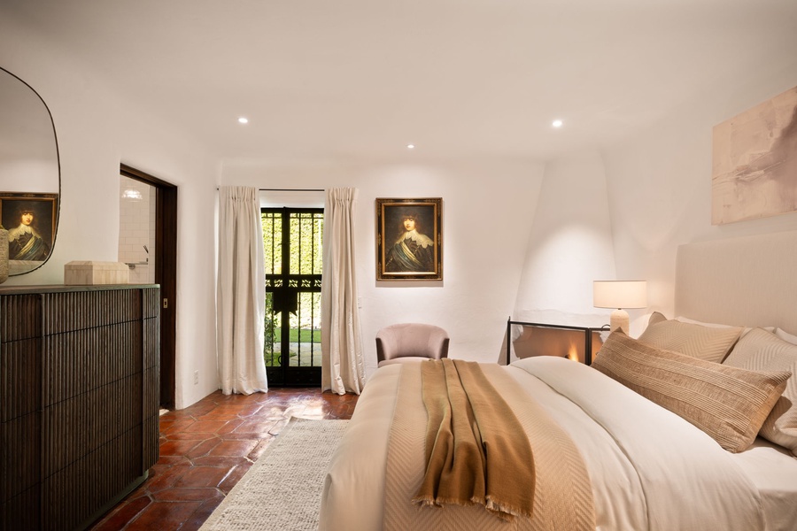 A calm, spacious bedroom with soft lighting and classic artwork — a quiet spot to relax after a day out in Montecito.